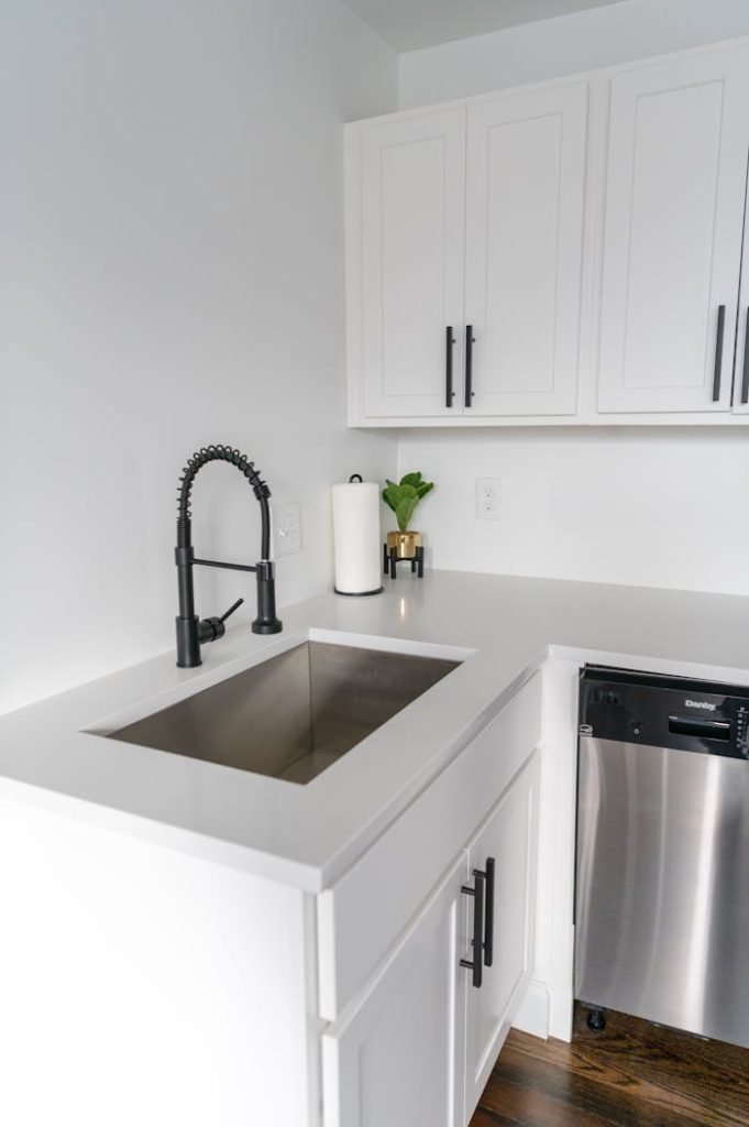 Bright white kitchen featuring sleek cabinets, stainless steel sink, and minimal design.